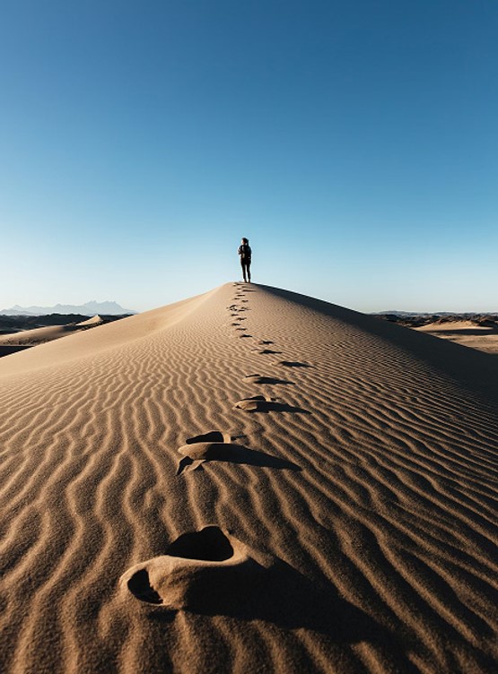 Traveler walking across desert sand dunes